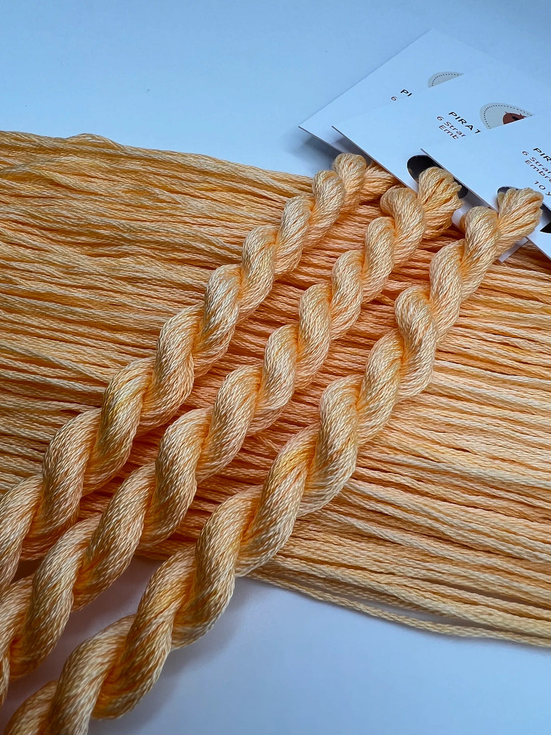 Three skeins of orange thread on a light blue background