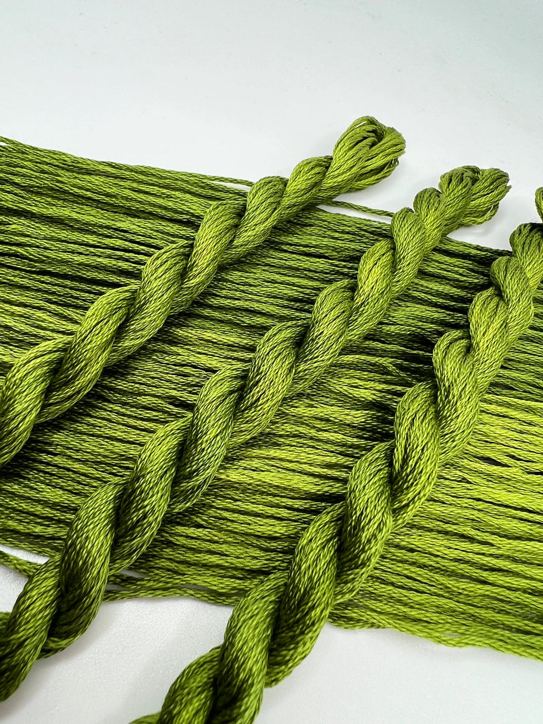 Close-up of green yarn with braided pattern on a white background