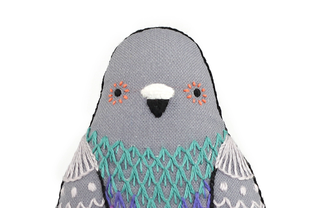 Stuffed toy penguin with gray body, teal patterned wings, and white face on a white background