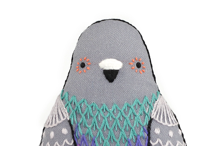 Stuffed toy penguin with gray body, teal patterned wings, and white face on a white background