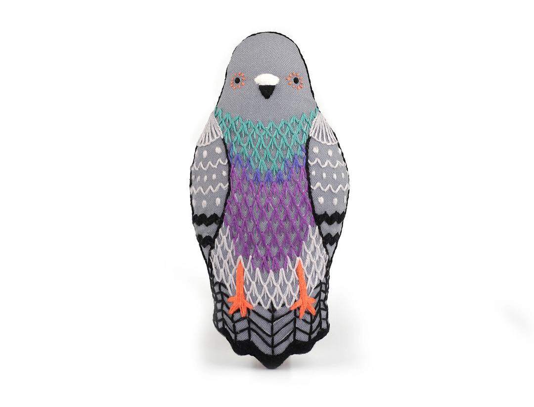 Knitted penguin toy with a patterned design on a white background