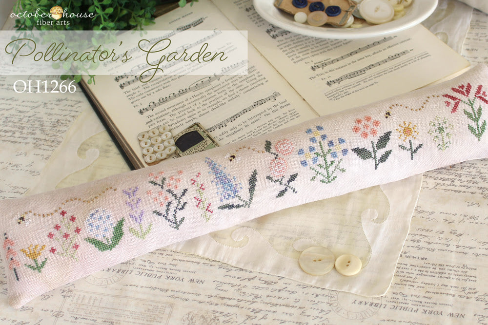 Cross-stitched fabric with floral patterns on a textured surface with 'Octoberhouse Fiber Arts' branding.