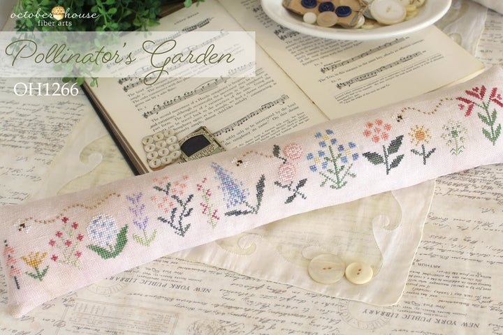 Cross-stitched fabric with floral patterns on a textured surface with 'Octoberhouse Fiber Arts' branding.