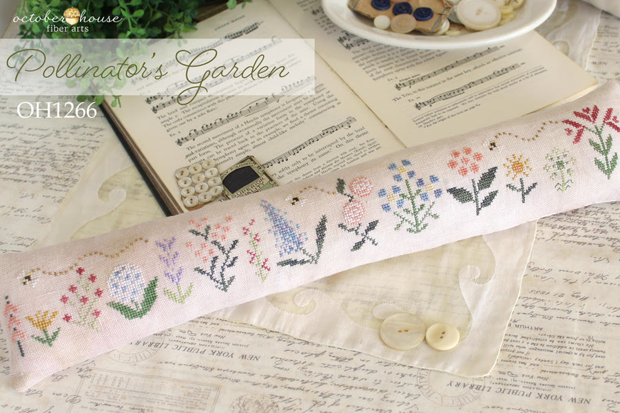 Cross-stitched fabric with floral patterns on a textured surface with 'Octoberhouse Fiber Arts' branding.