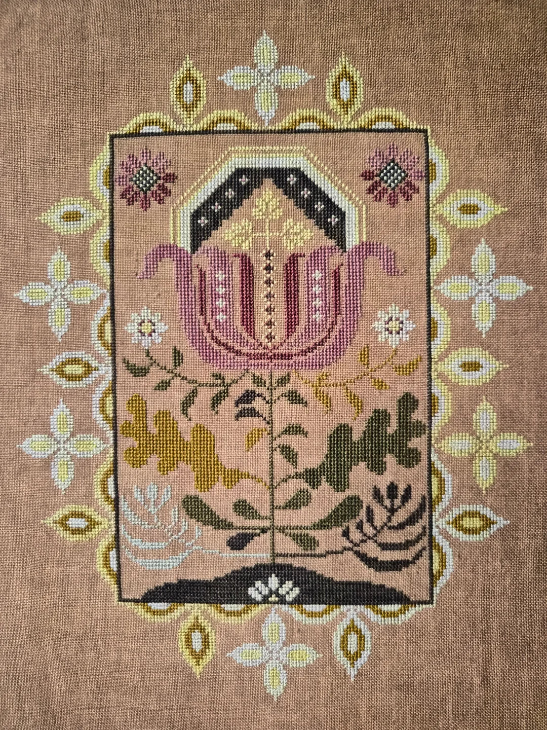Embroidered design of a flower with floral border on a brown fabric background