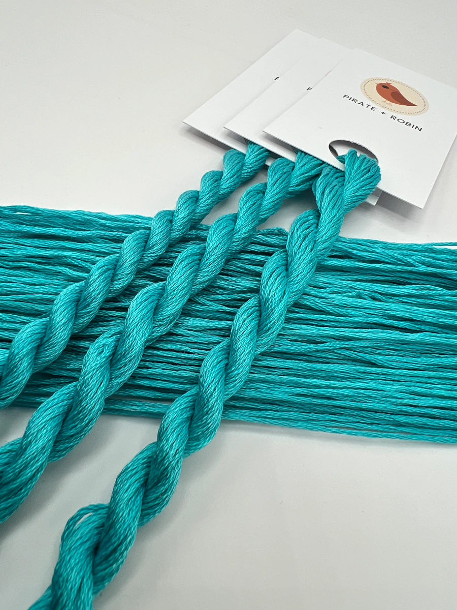 Turquoise thread  on a white background with brand cards.