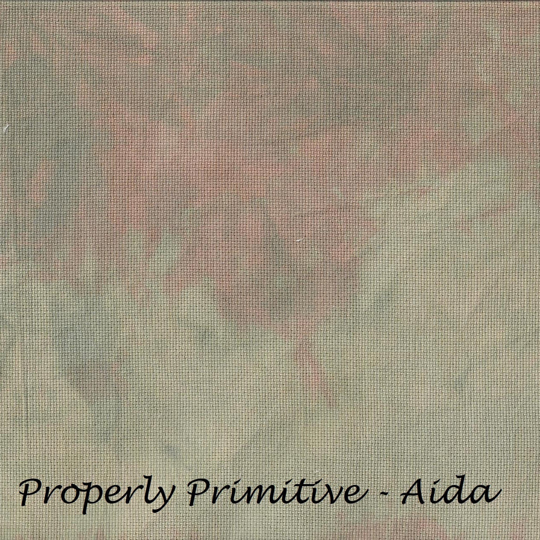 A square fabric or material swatch with a mottled, textured pattern in muted gray-green, dusty pink, and beige tones, with the text 'Properly Primitive - Aida' printed in black at the bottom.