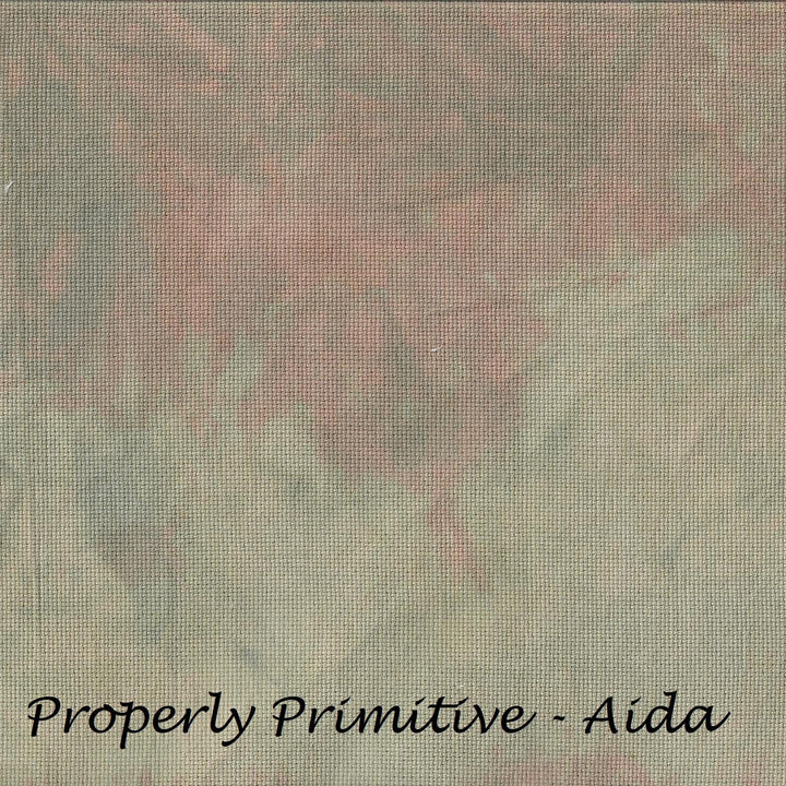 A square fabric or material swatch with a mottled, textured pattern in muted gray-green, dusty pink, and beige tones, with the text 'Properly Primitive - Aida' printed in black at the bottom.