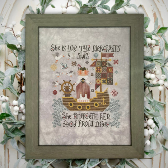 Framed cross-stitched artwork with ship design and text, surrounded by decorative greenery.