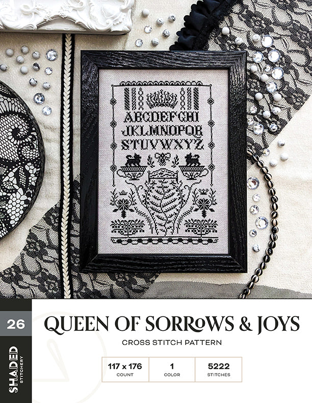 Cross stitch pattern titled 'Queen of Sorrows & Joys' on a textured surface with decorative elements.