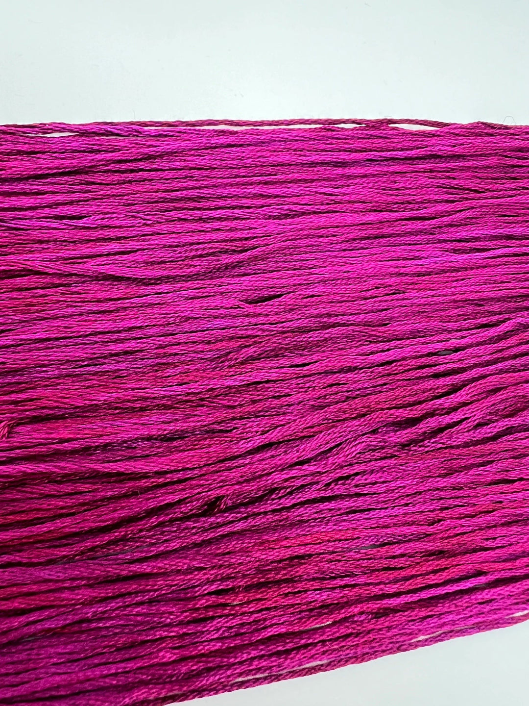 Close-up of pink embroidery floss on a white background