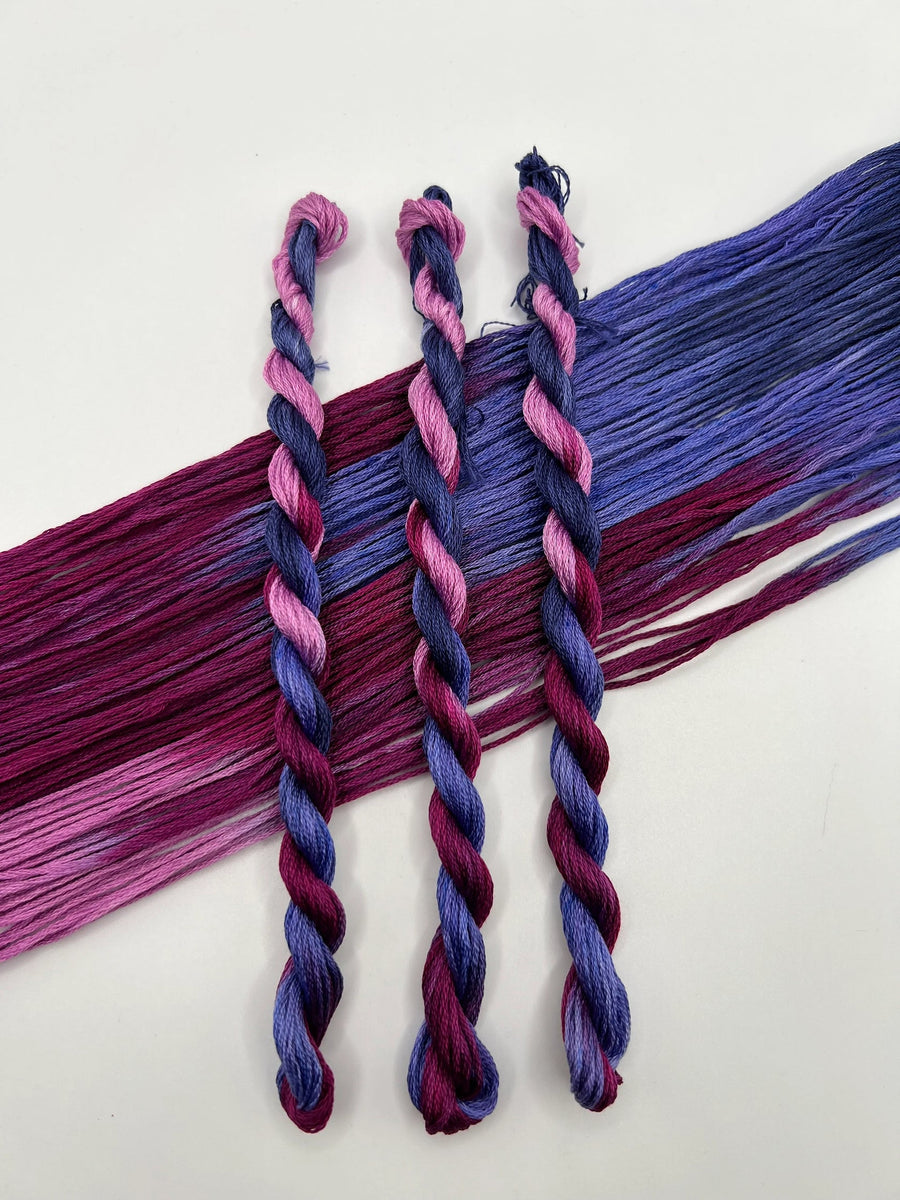 Three braided hair extensions in purple and pink on a white background