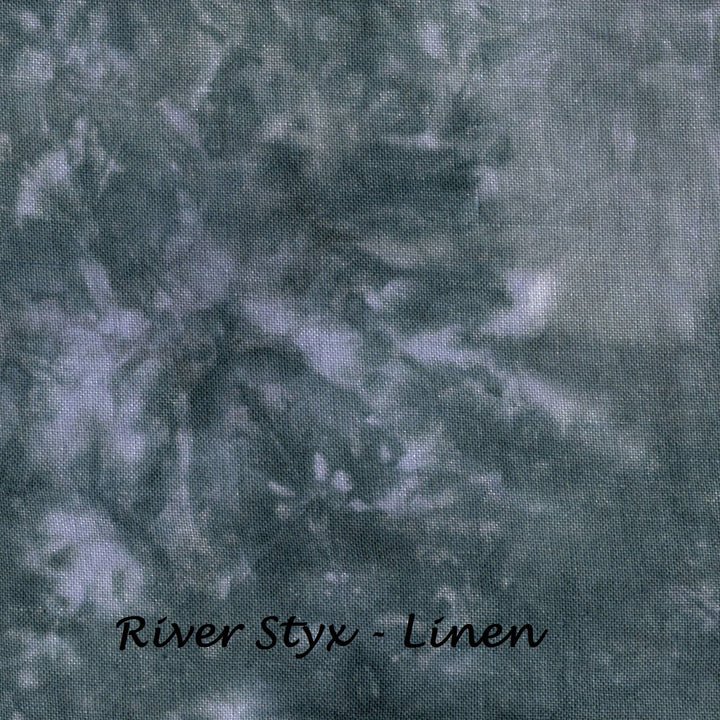 A close-up of a textured fabric with a mottled, tie-dye style pattern in muted blue-gray, gray, and off-white tones. The text 'River Styx - Linen' is printed in black at the bottom center.