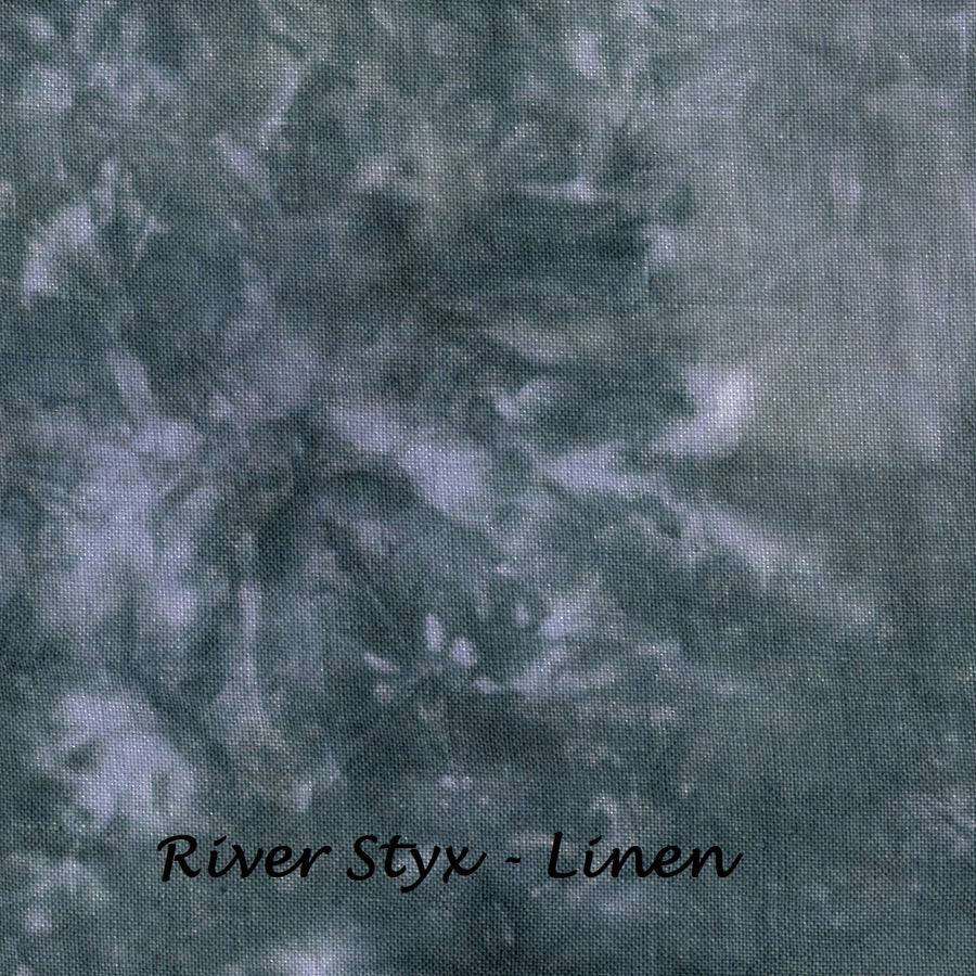 A close-up of a textured fabric with a mottled, tie-dye style pattern in muted blue-gray, gray, and off-white tones. The text 'River Styx - Linen' is printed in black at the bottom center.
