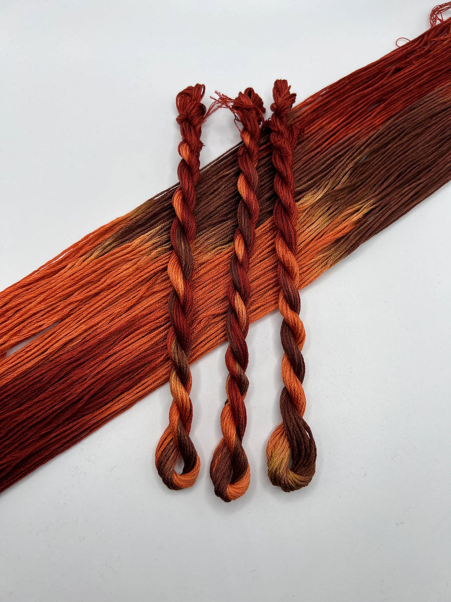 Three braided hair extensions with brown and orange color gradient on a white background