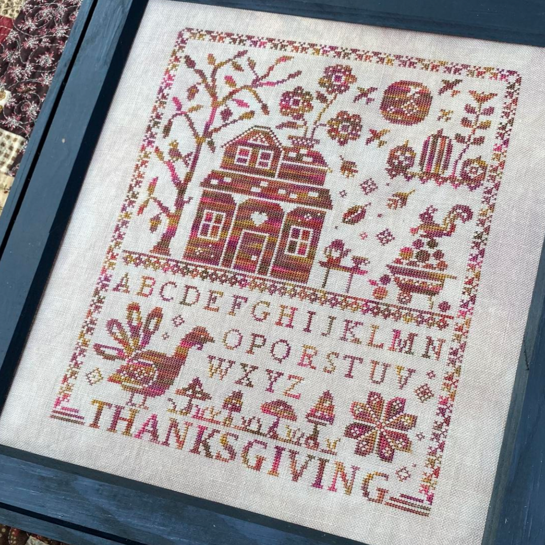 Cross-stitched sampler with Thanksgiving design and text.