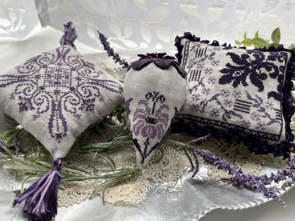 Decorative pillows with embroidered patterns and tassels on a textured surface.