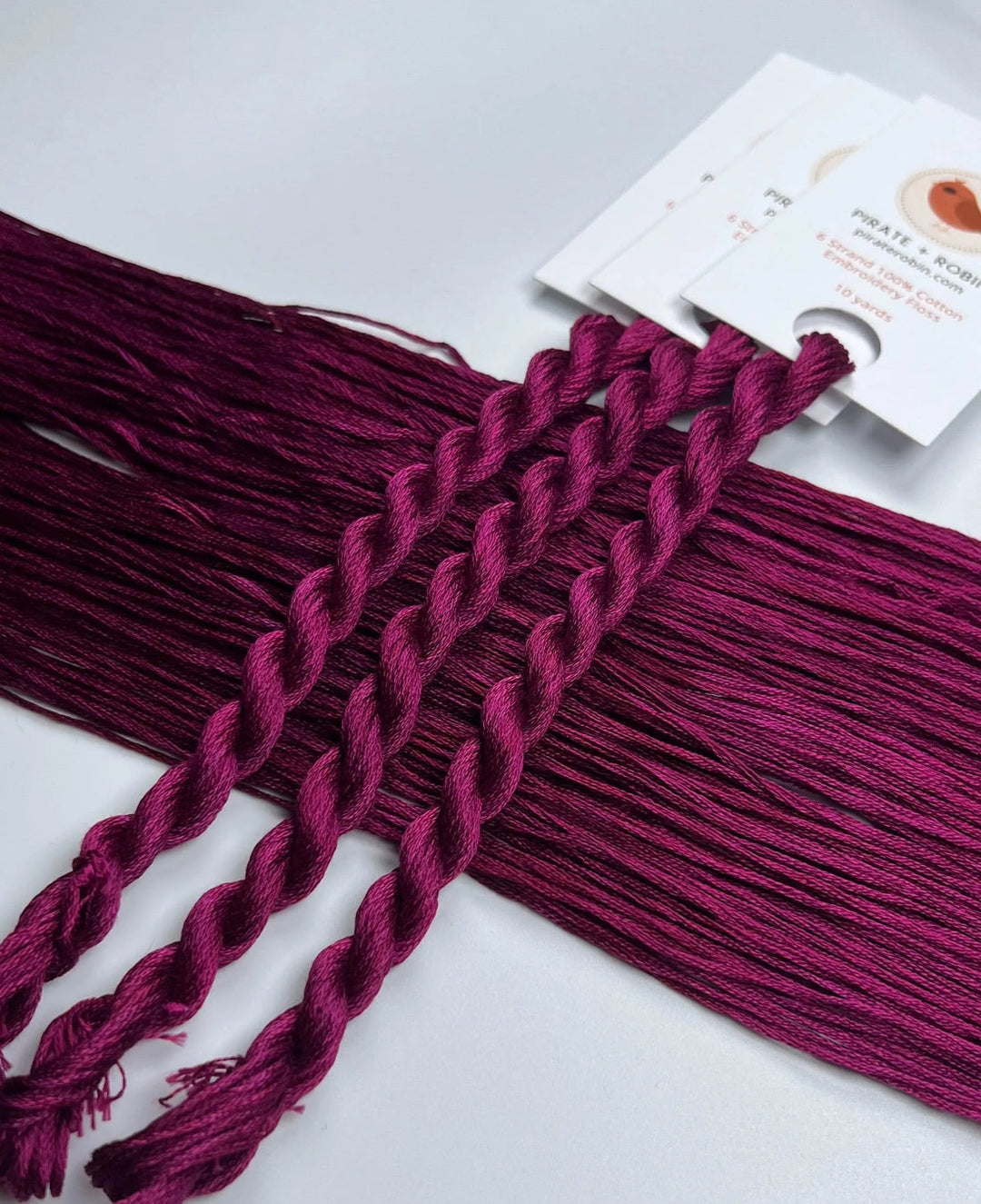 Braided purple thread with a white card in the background