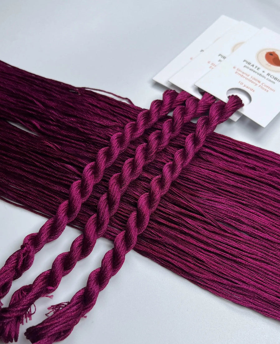 Braided purple thread with a white card in the background
