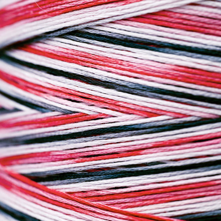 Close-up of variegated yarn wound into a skein, showing alternating stripes of red, white, and black.