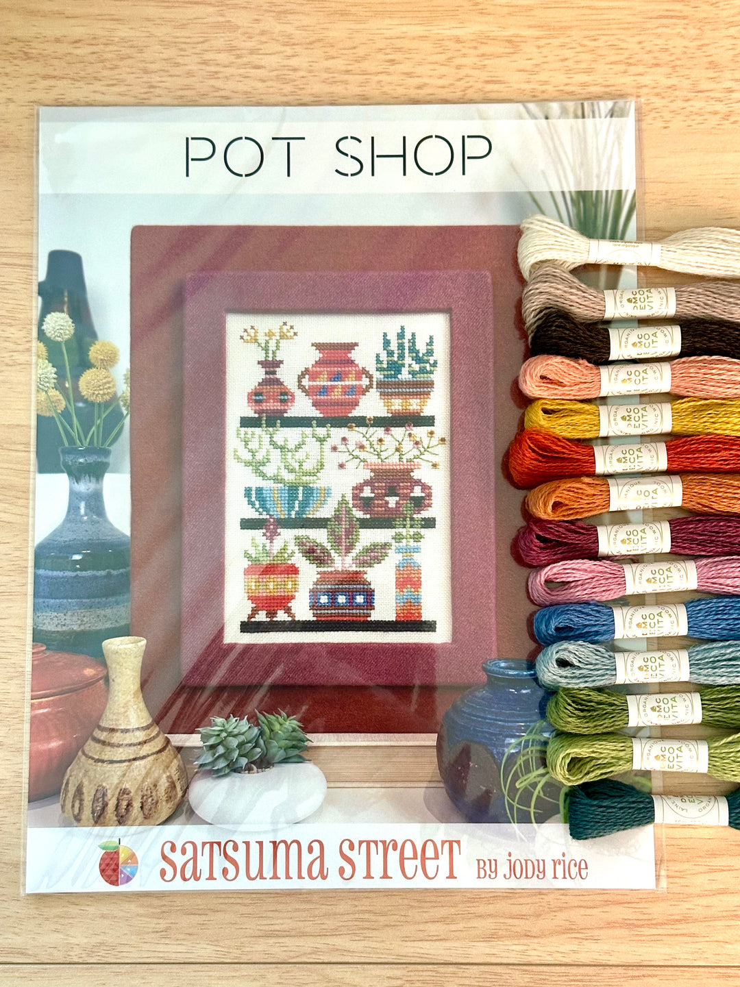 Cross-stitch pattern with pottery and yarn on a wooden surface, featuring 'Satsuma Street' branding.