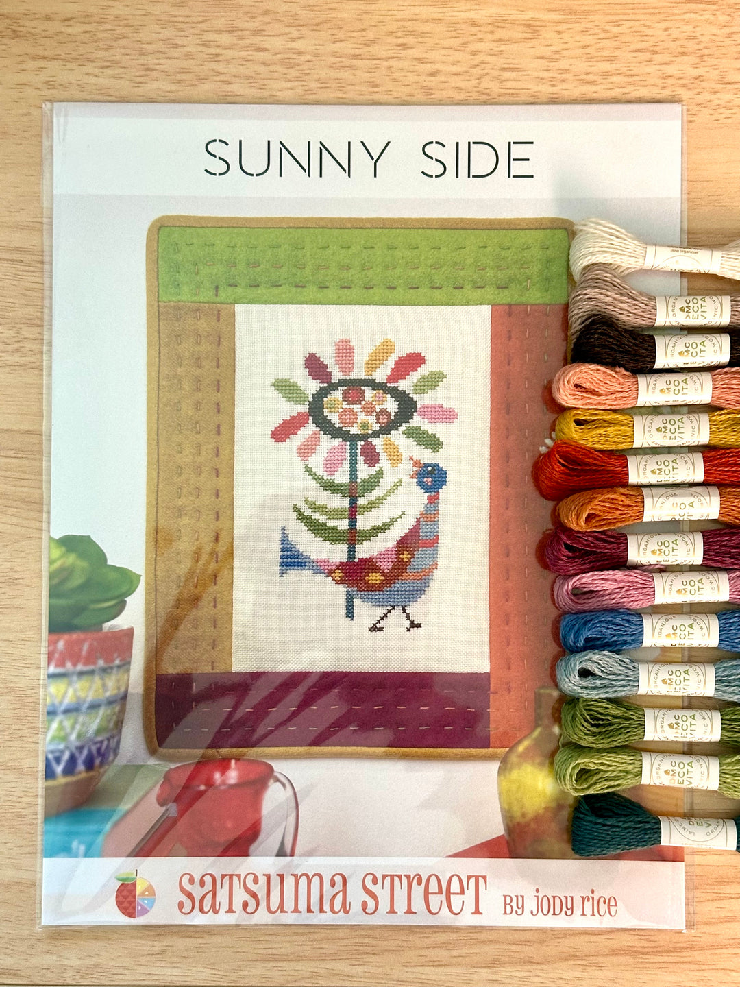 Cross-stitch kit with colorful threads and a pattern on a wooden surface