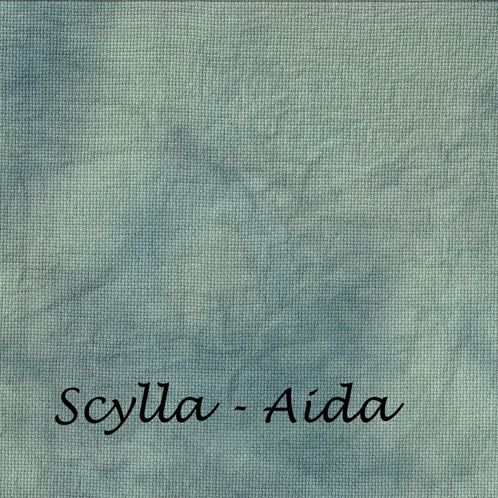 A square fabric swatch with a mottled, textured pattern in shades of dusty teal, blue, and gray, featuring the text 'Scylla - Aida' printed in black cursive at the bottom.