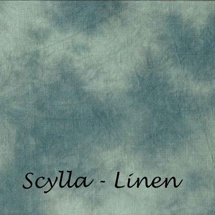 A square fabric swatch with a mottled, tie-dye style pattern in dusty teal, blue, and off-white, with the text 'Scylla - Linen' printed in black script at the bottom.