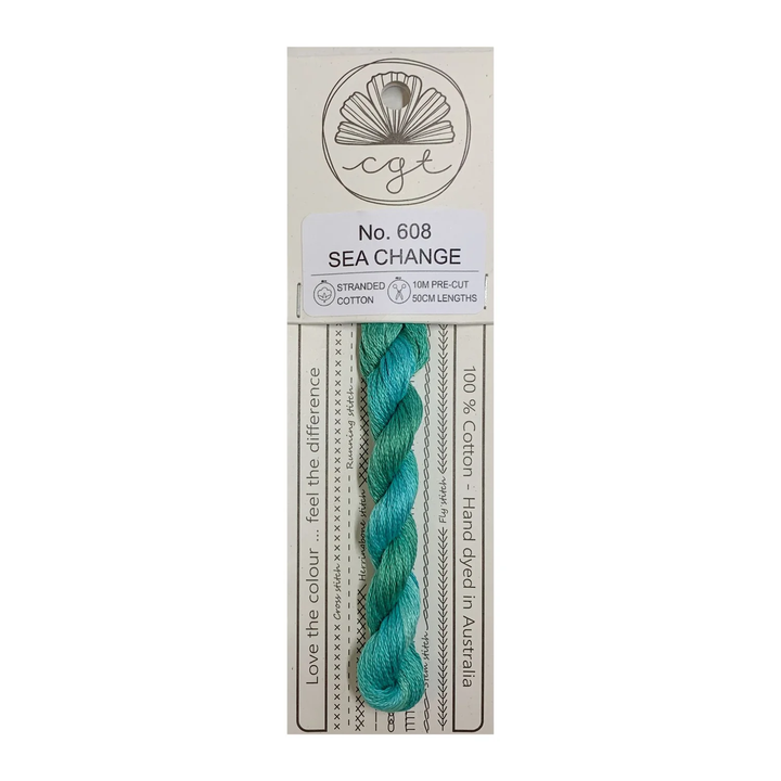 A skein of hand-dyed blue-green embroidery floss labeled 'Sea Change' from Cottage Garden Threads, with product information on the packaging.