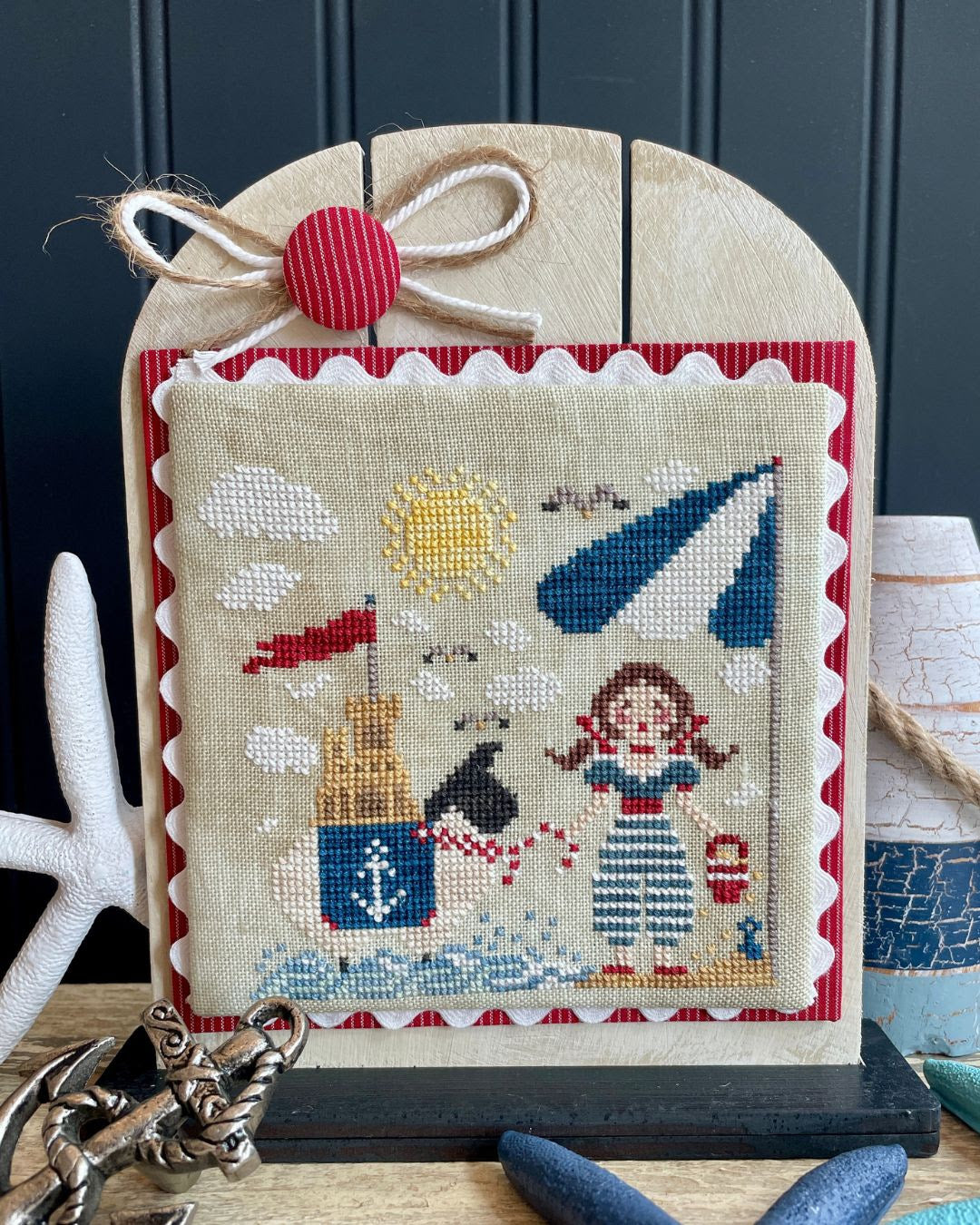 Decorative cross-stitched picture with a nautical theme on a stand.