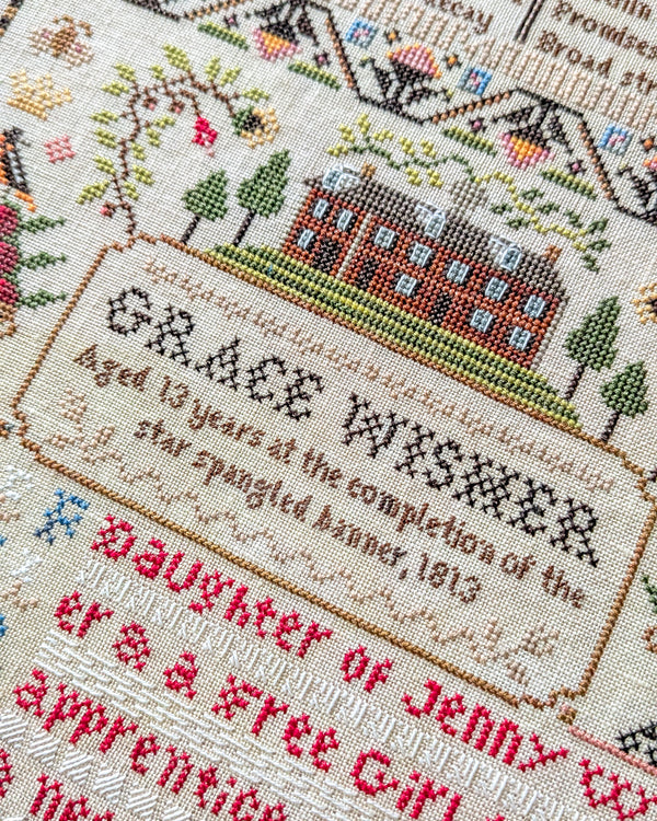 Cross-stitched sampler with text and a small landscape design