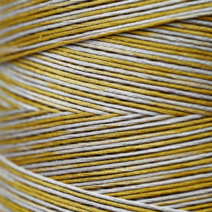 A close-up of tightly wound yarn or thread in a herringbone pattern, showing alternating strands of mustard yellow and light gray.