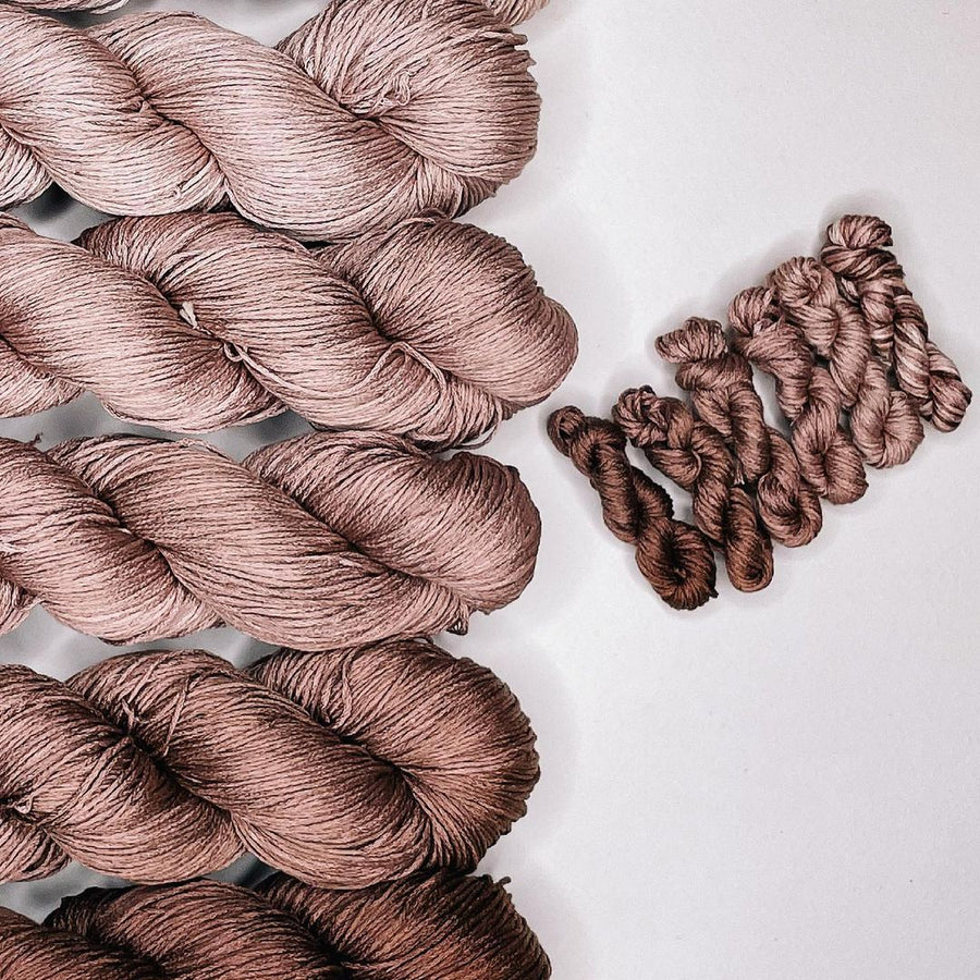 Multiple skeins of beige and brown yarn arranged in parallel on a surface, representing the Skin Tone Collection.