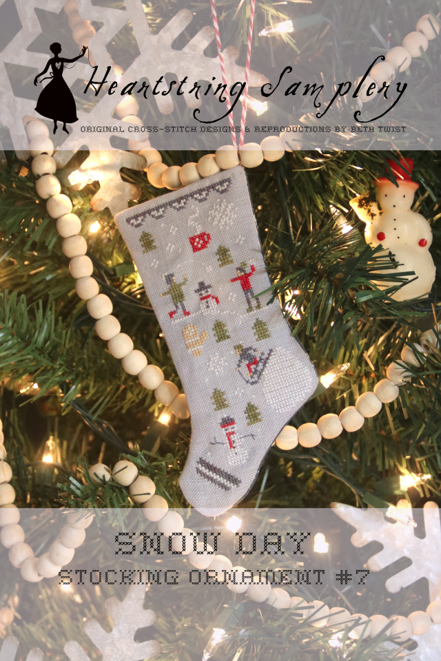 Cross-stitched stocking ornament on a Christmas tree with 'Heartspring Sam plew' branding.