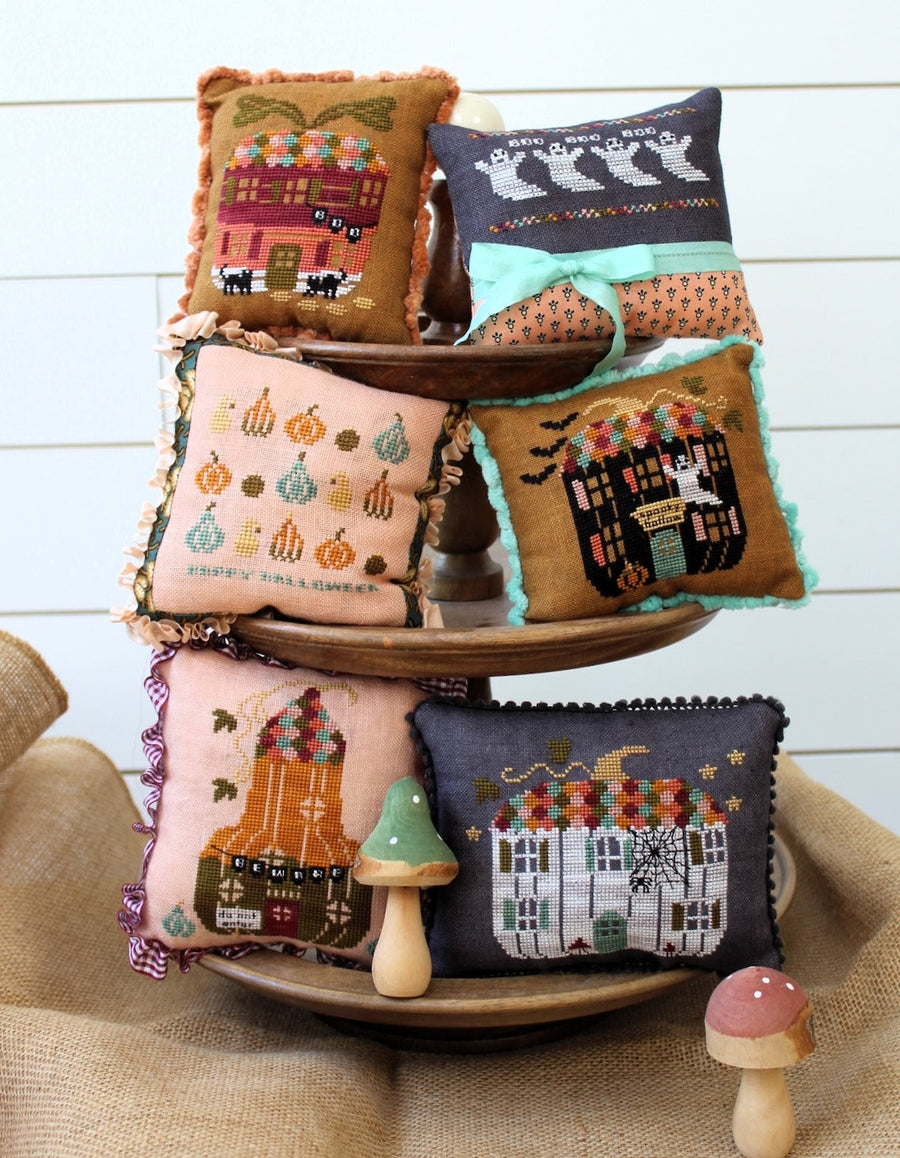 Collection of embroidered pillows on a wooden tiered stand with a rustic background.
