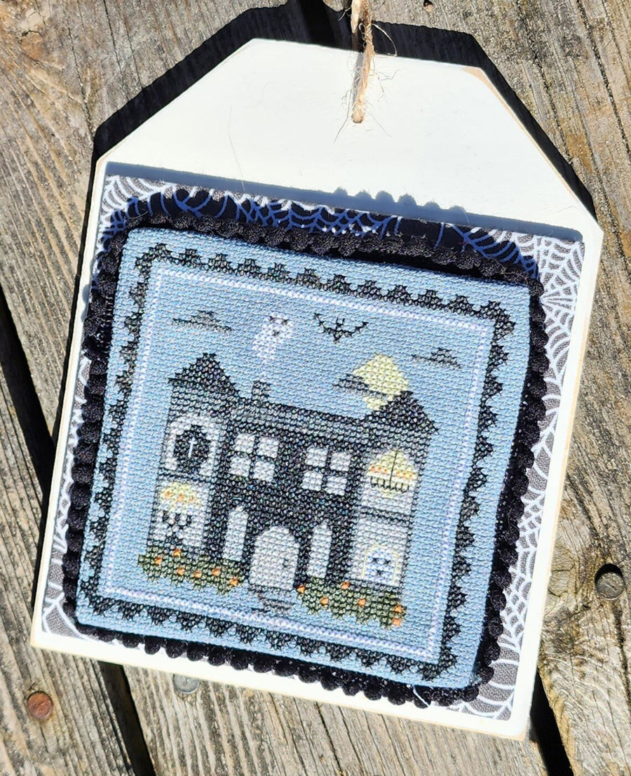 Embroidered house design on a wooden surface