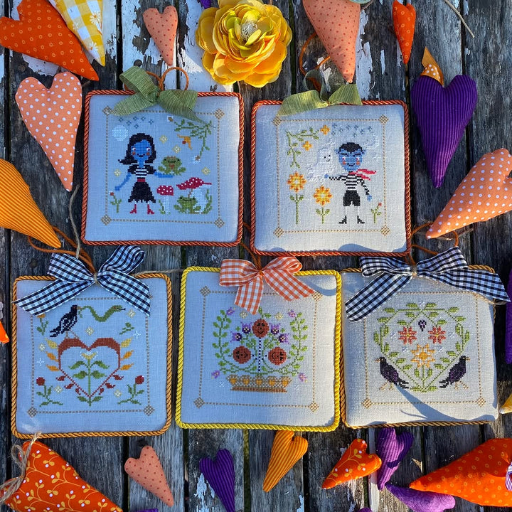 Set of cross-stitched halloween autumn ornaments with decorative elements on a wooden surface.