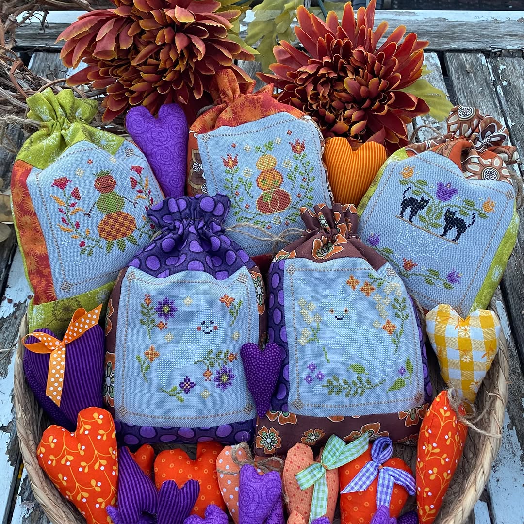 Decorative items including embroidered cloths, pumpkins, and a basket on a wooden surface.