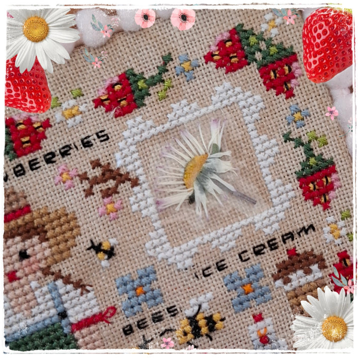 A square cross-stitch sampler featuring whimsical designs including a girl, strawberries, bees, daisies, and text reading 'BERRIES' and 'ICE CREAM' on a beige linen background.