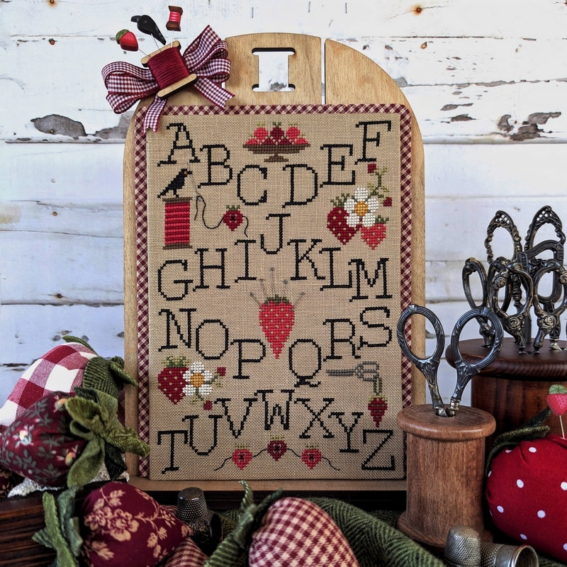 Decorative cross-stitched alphabet on a wooden board with rustic background