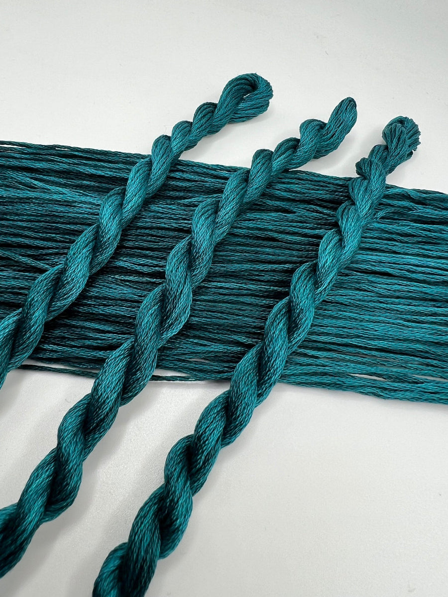Teal braided thread skeins on a white background