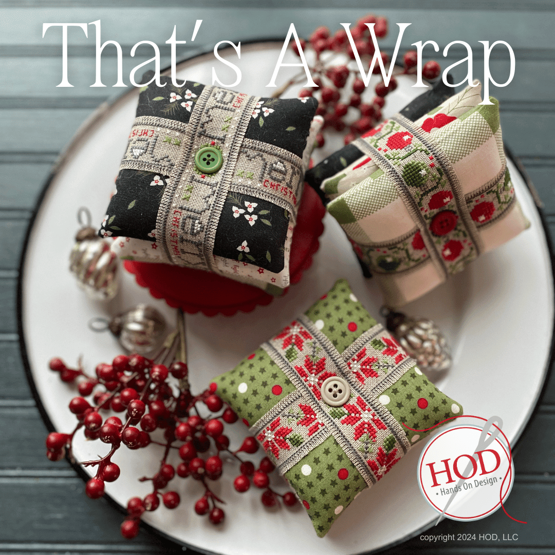 Decorative pillows with Christmas patterns on a plate with berries and ornaments, featuring 'HOD' logo.