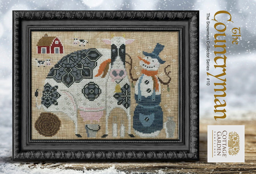 Framed cross-stitched artwork featuring farm animals and a snowman on a snowy background.