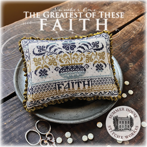 Decorative pillow with cross-stitch design on a wooden surface, featuring the brand 'Summer House Stitche Works'.