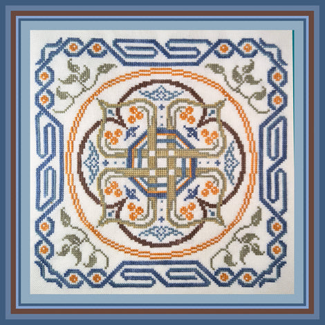 A square cross-stitch pattern or finished textile design featuring a symmetrical Celtic-style knotwork and floral motif. The design is stitched on white fabric with blue, orange, brown, and green thread, framed by a layered blue and brown border.