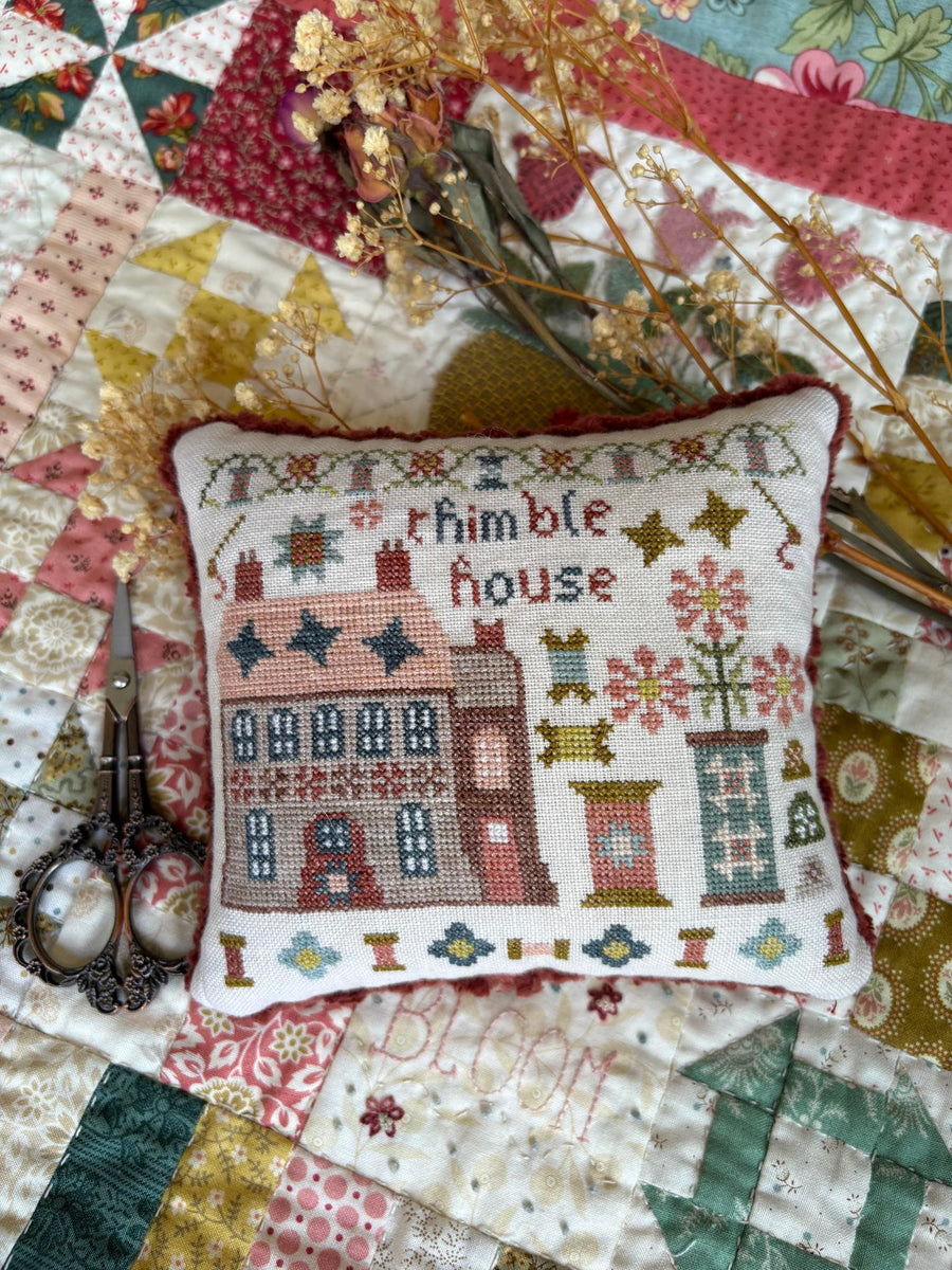 Decorative pillow with cross-stitch design on a patchwork quilt