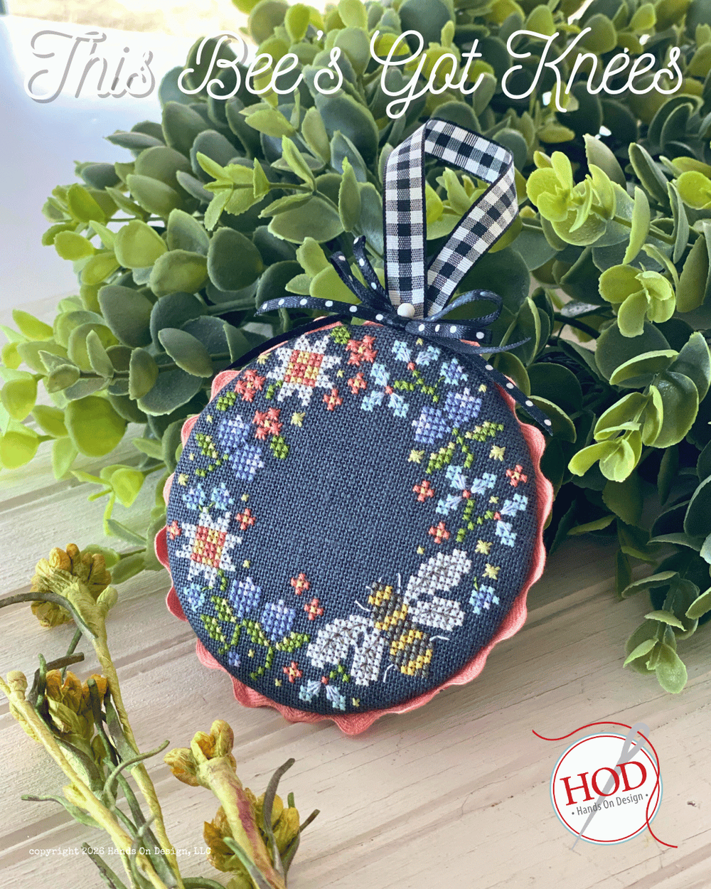 Decorative cross-stitched coin purse ornament floral pattern on a green leafy background, featuring 'This Bee's Got Knees' text and HOD logo.