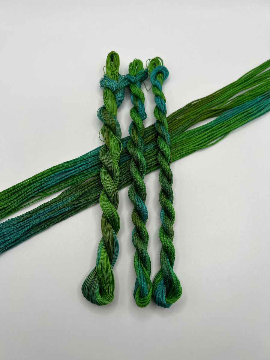 three braided green and blue thread skeins on a white background
