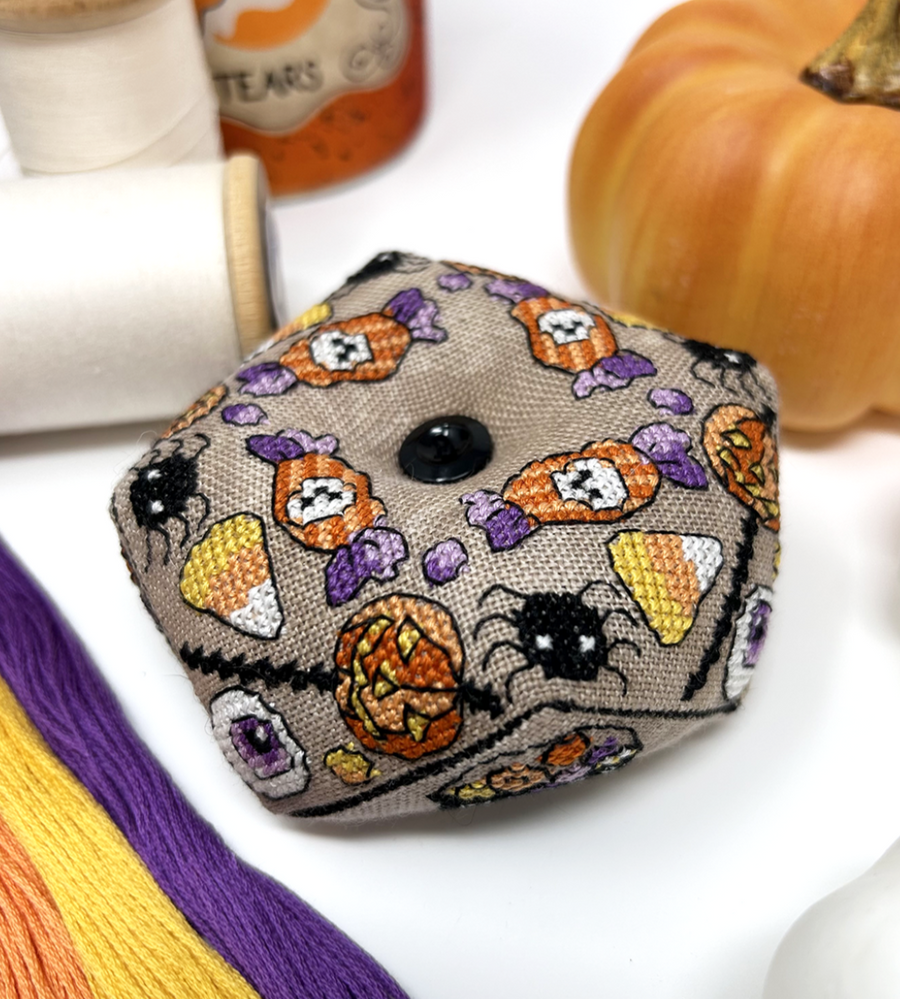 Decorative Halloween-themed pouch with pumpkins, ghosts, and candy corn on a white background.