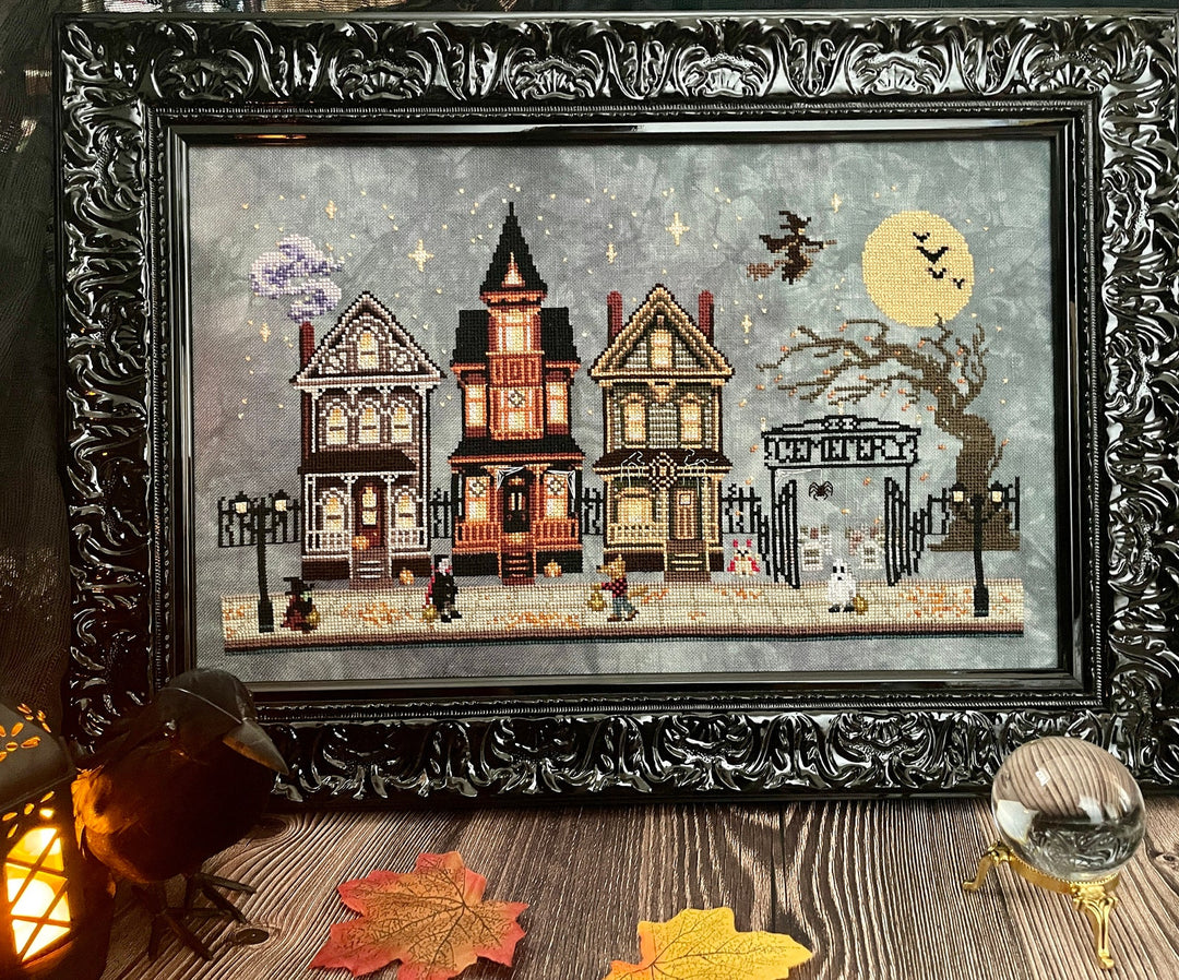 Framed artwork of a Halloween-themed village scene with ornate black frame.